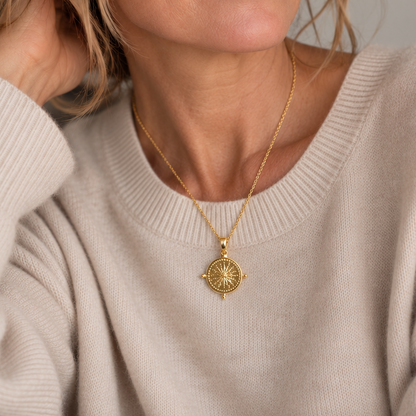 Woman wearing the St. Moritz gold sunburst medallion necklace with a cream cashmere sweater