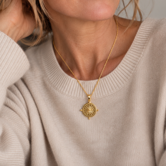 Woman wearing the St. Moritz gold sunburst medallion necklace with a cream cashmere sweater